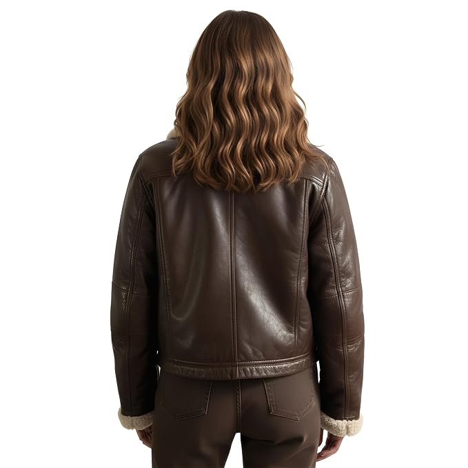 A woman viewed from behind wearing a dark brown leather jacket with a light beige shearling lining at the collar and cuffs, paired with matching brown pants, against a solid white background.