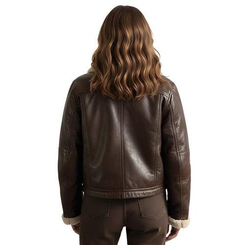 A woman viewed from behind wearing a dark brown leather jacket with a light beige shearling lining at the collar and cuffs, paired with matching brown pants, against a solid white background.
