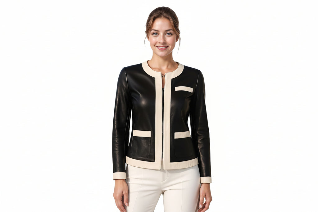 A woman modeling a black faux-leather jacket with cream trim details, paired with cream pants, against a solid white background.