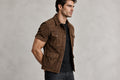 Side view of the olive green Noble Forge Vintage Brown Suede Leather Jacket featuring a shirt collar, button closure, and four utility pockets.   