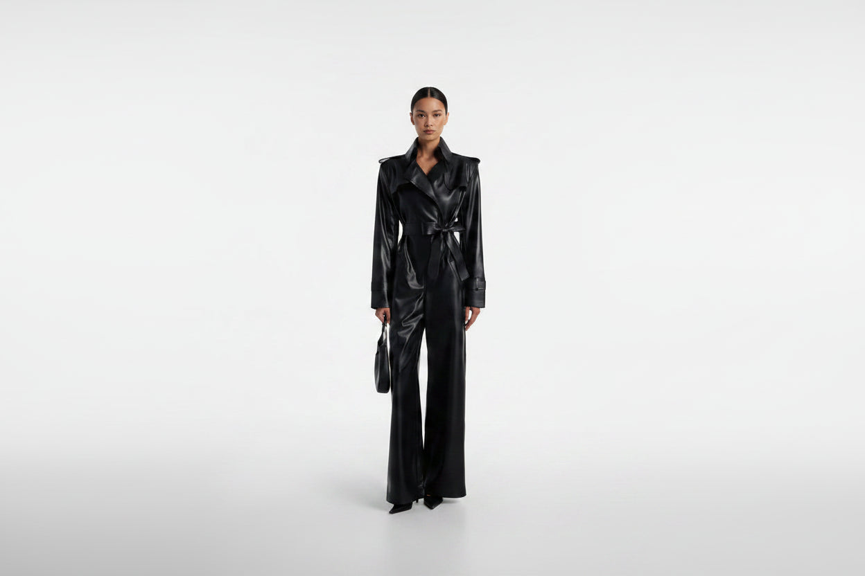Sienna Noir women's jet black genuine Nappa lambskin leather jumpsuit featuring a trench coat style notch collar, chest storm flap, shoulder epaulettes, self-tie leather waist belt, wide-leg trousers, and custom made-to-measure fitting across the UK, USA, and Australia.